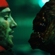A man with a red uniform and a grimy face stands face-to-face with a terrifying monster.